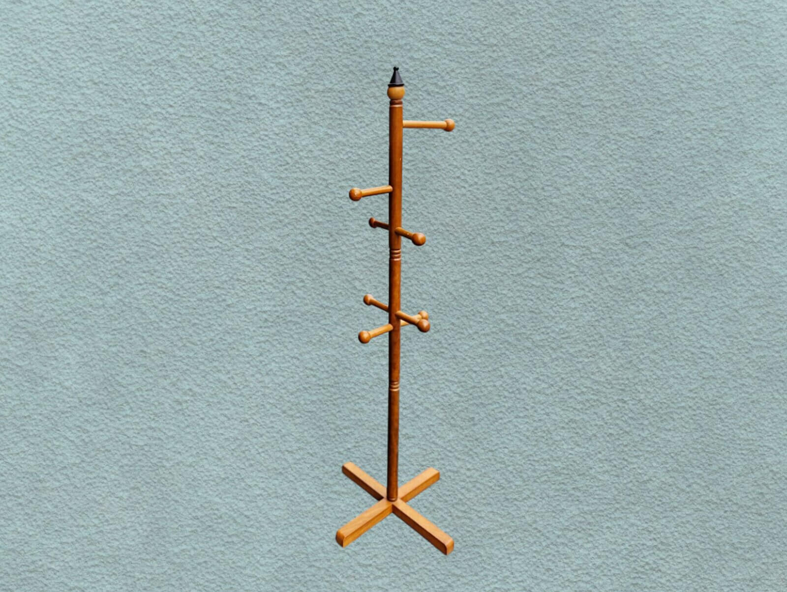 Minimal wooden coat rack against a textured green background